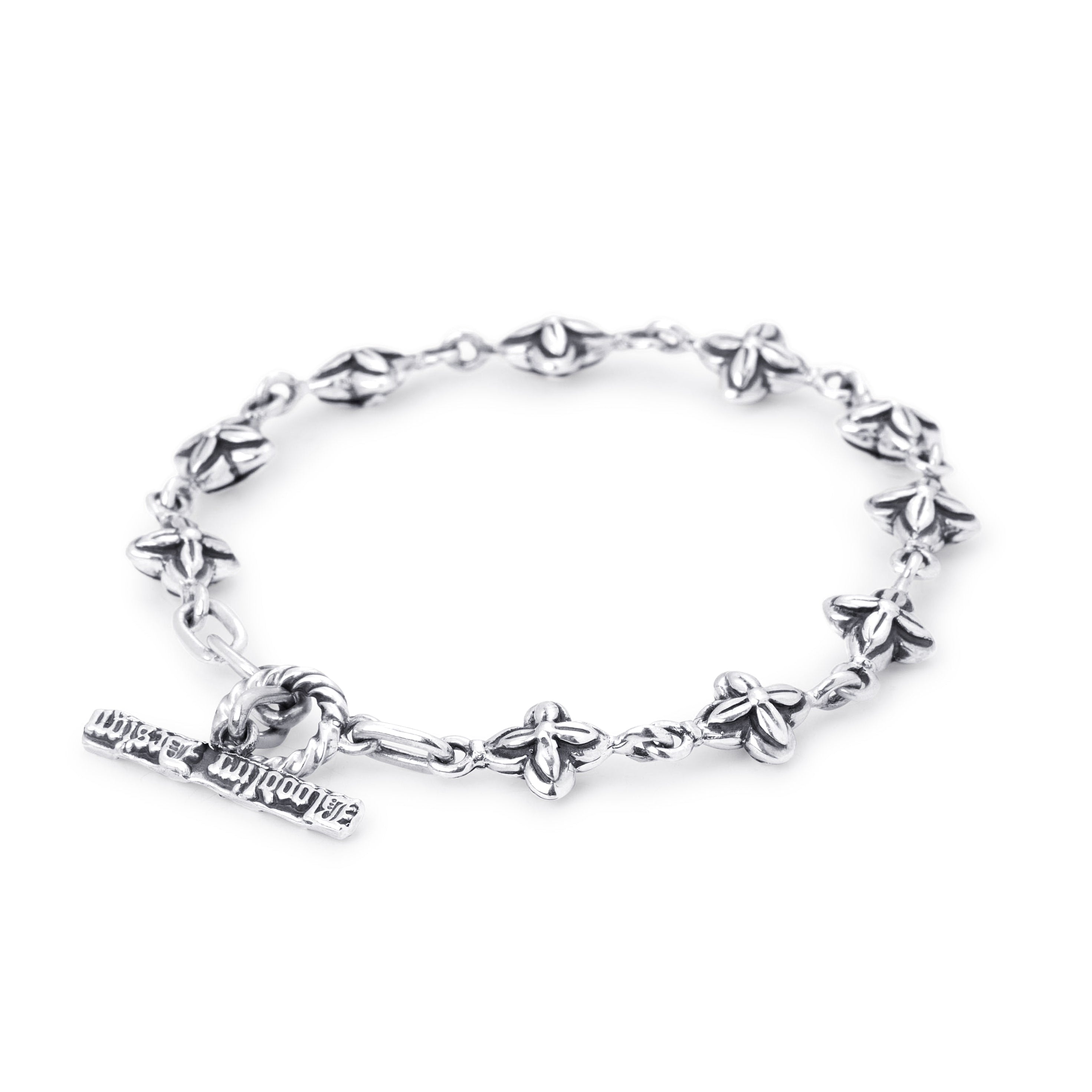 A silver-toned metal bracelet featuring a repeating floral pattern and a small dangling charm. 