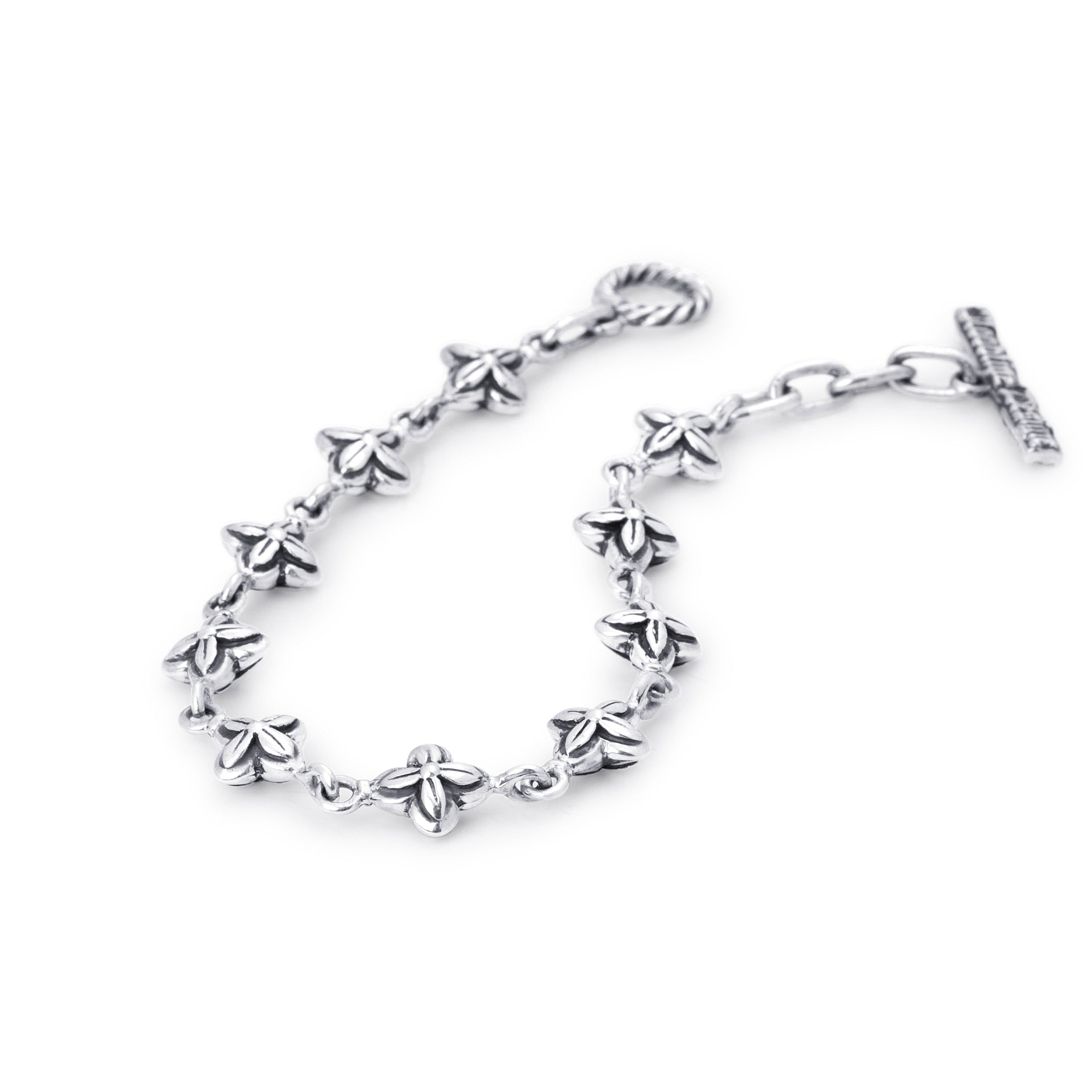 A sterling silver chain bracelet featuring small, detailed flower motifs along the chain, finished with a twisted lobster clasp on one end and an extension chain with a flat bar clasp on the other, shown against a plain white background.