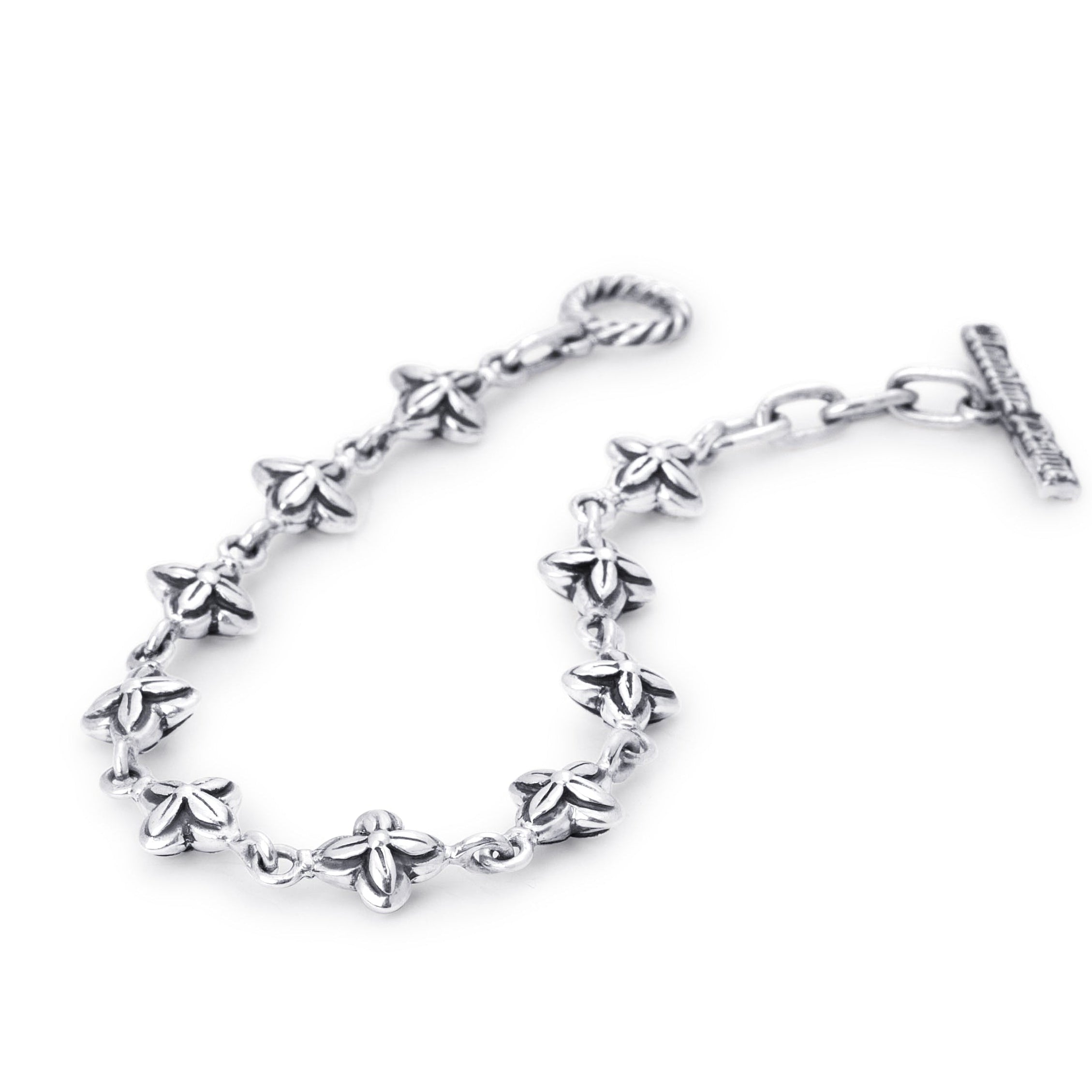 A sterling silver chain bracelet featuring small, detailed flower motifs along the chain, finished with a twisted lobster clasp on one end and an extension chain with a flat bar clasp on the other, shown against a plain white background.