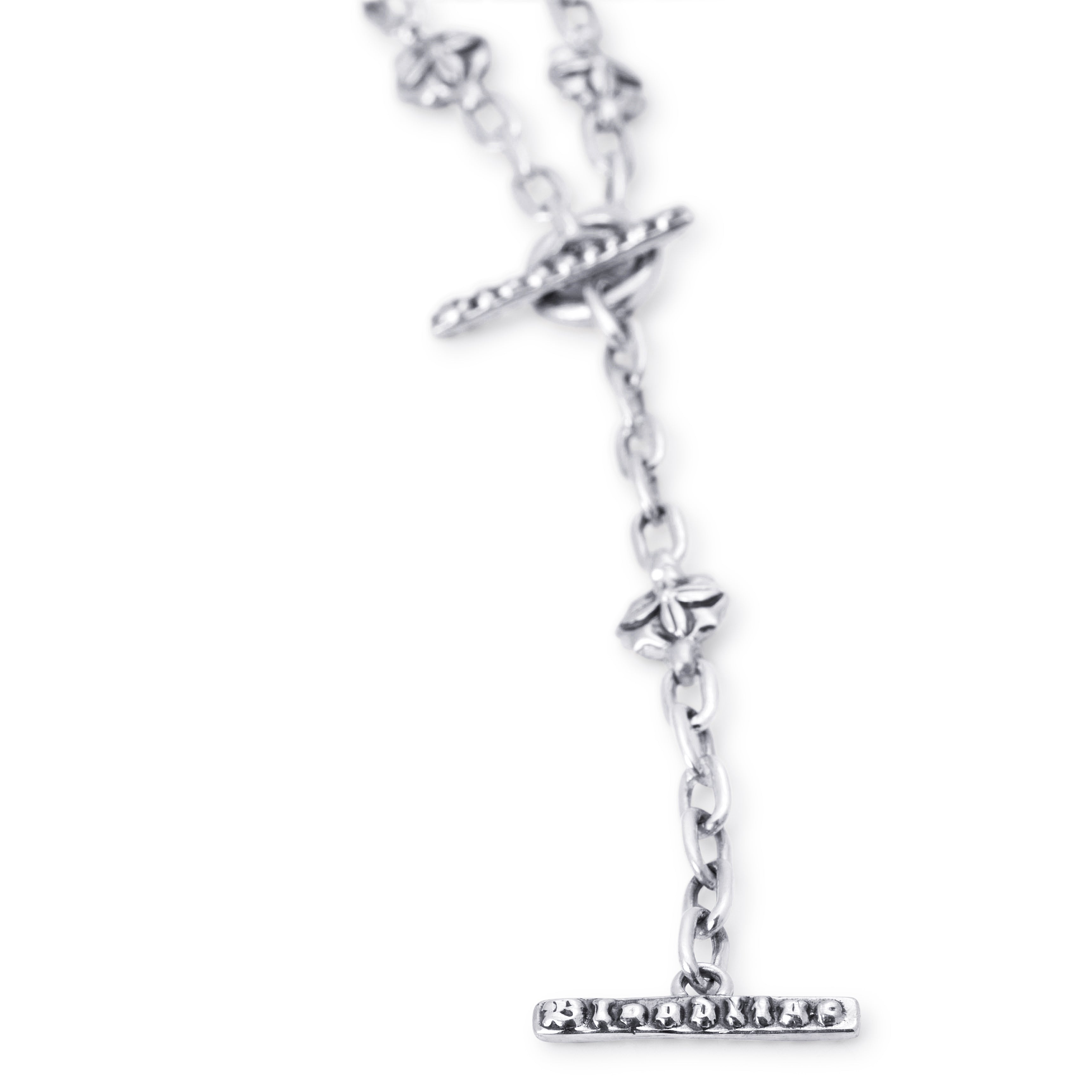 A silver lariat necklace with a T-bar and Floral links on a white background. 