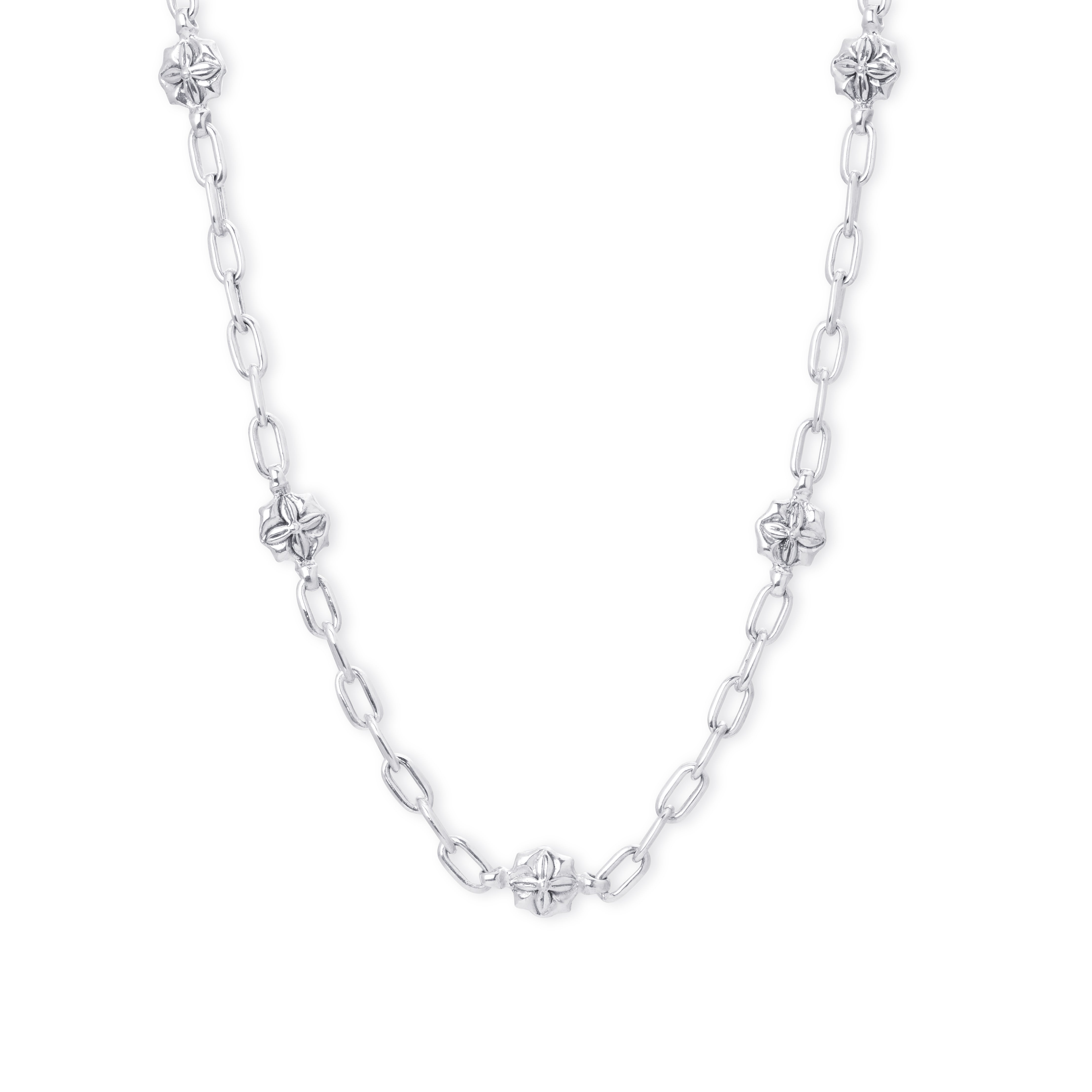 A silver chain necklace featuring alternating elongated oval links and small four-petal flower charms, displayed against a solid white background.