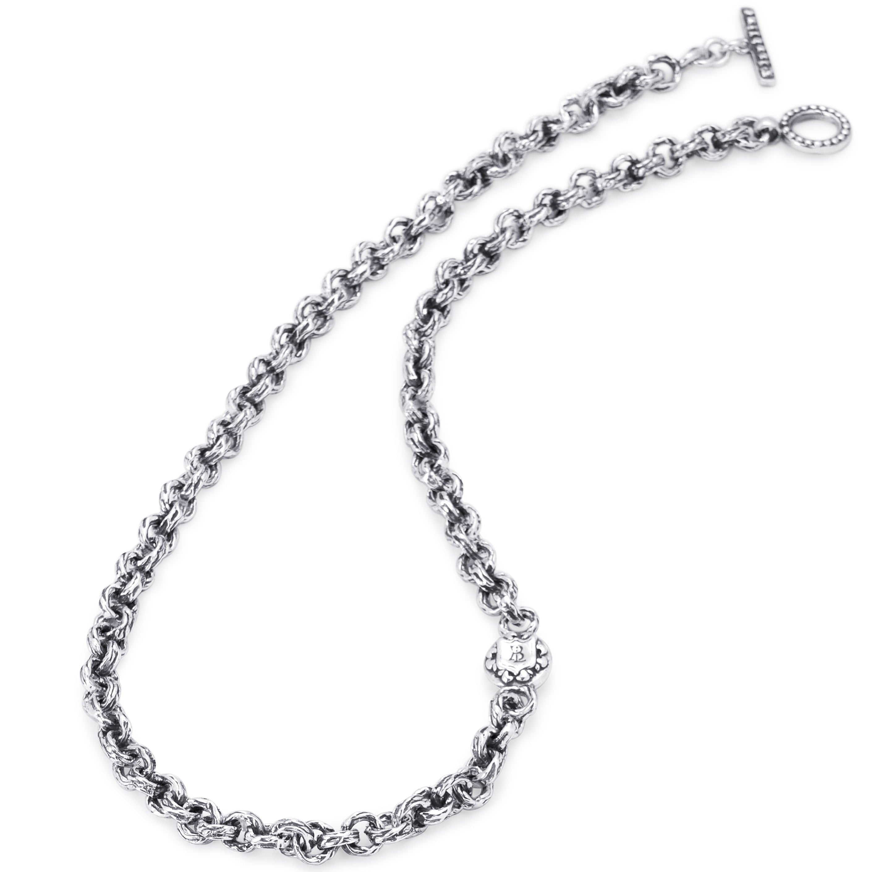 A silver-toned metal chain necklace with a textured, woven link design, featuring a lobster clasp and a toggle clasp on a solid white background.
