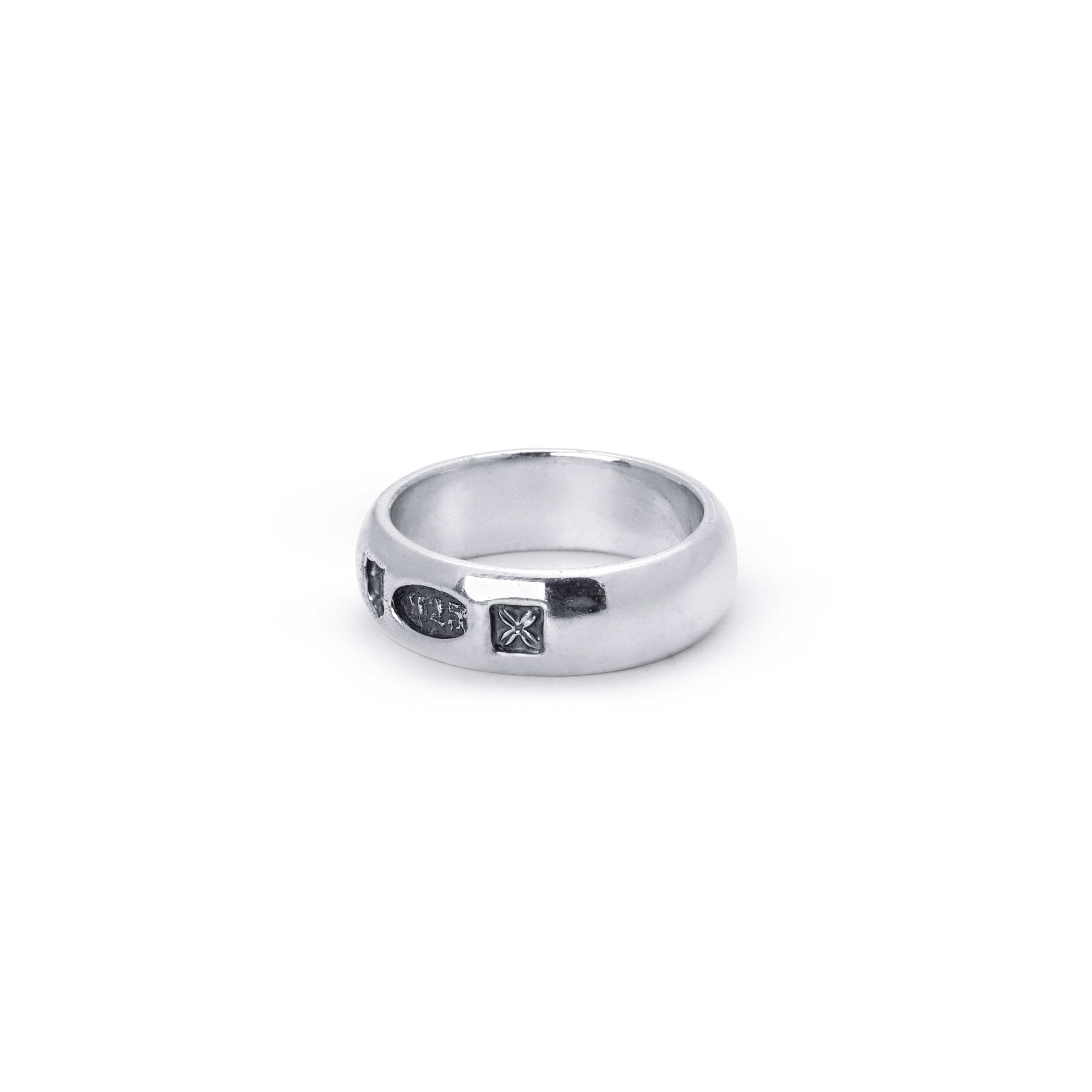 A silver band ring with three small dark hallmarks, photographed on a clean white background.