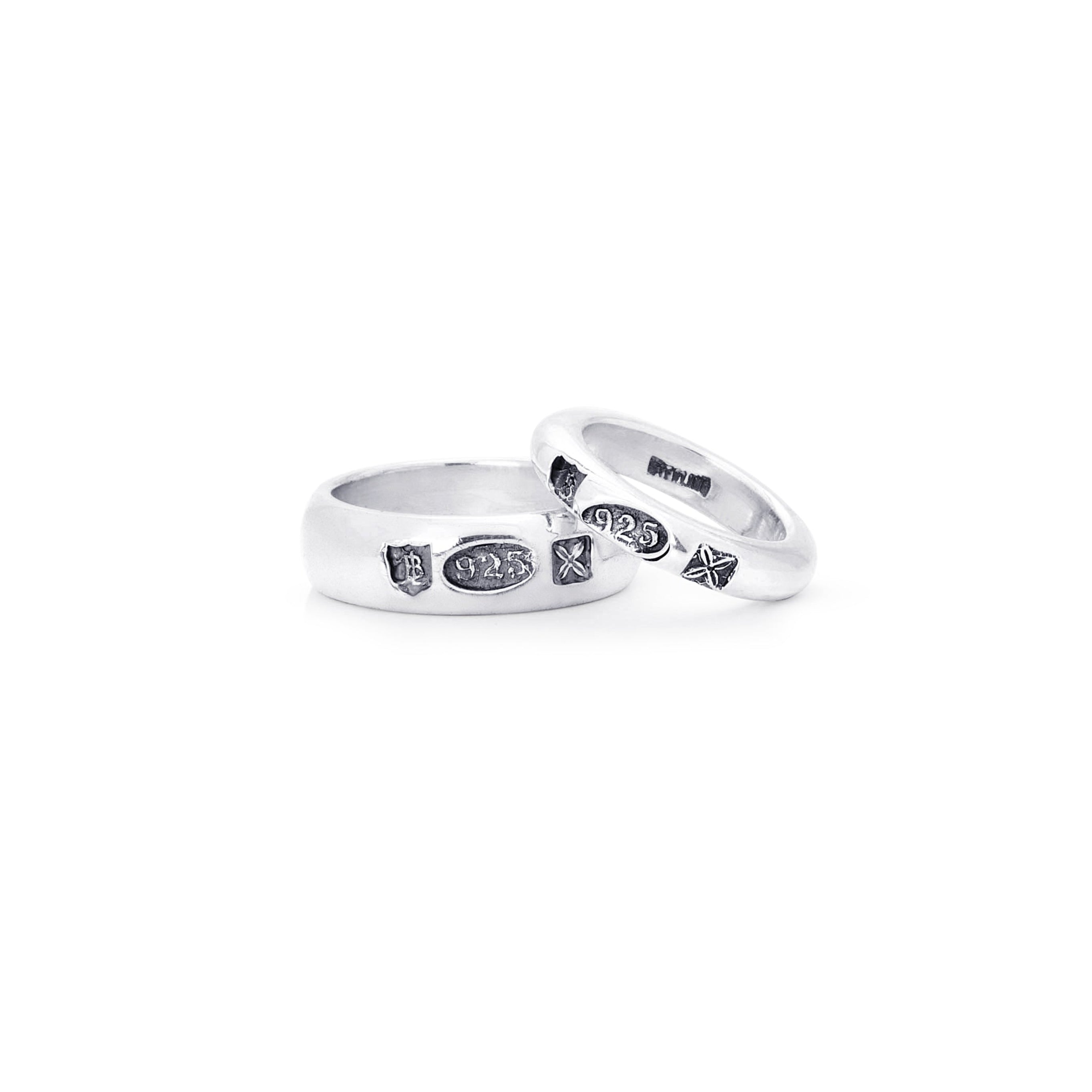 Two silver bands with small black hallmark stamps displayed on a clean white background.