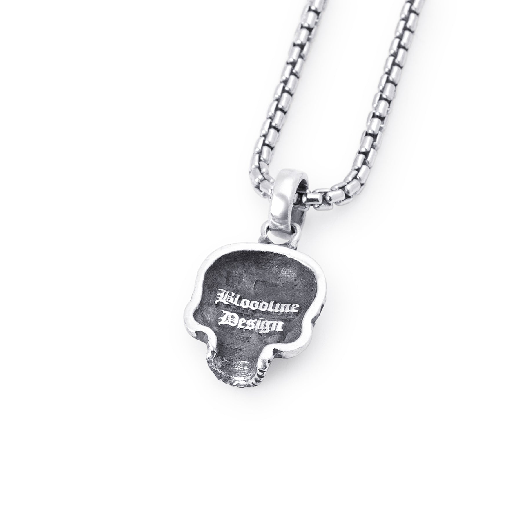 A detailed skull pendant necklace on a matching box chain, shown against a plain white background. The pendant features the text  