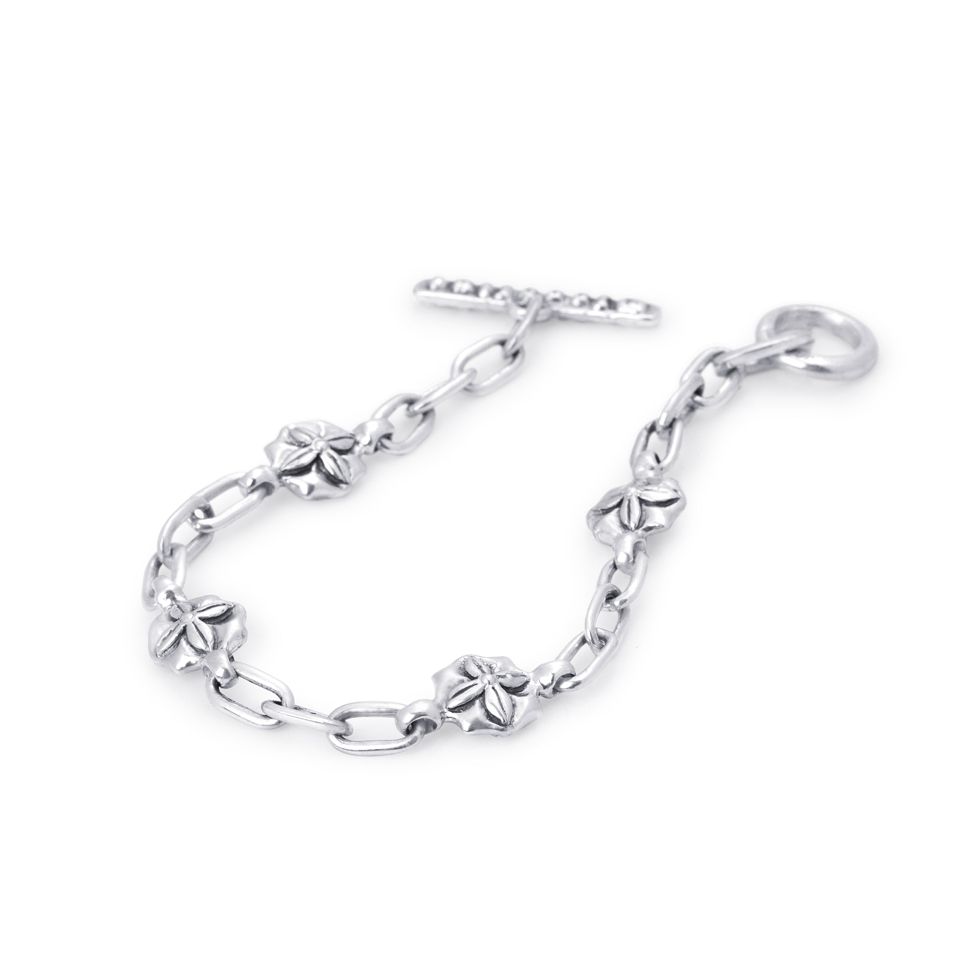 A silver chain bracelet featuring alternating floral motifs and a toggle clasp, displayed on a clean white background.