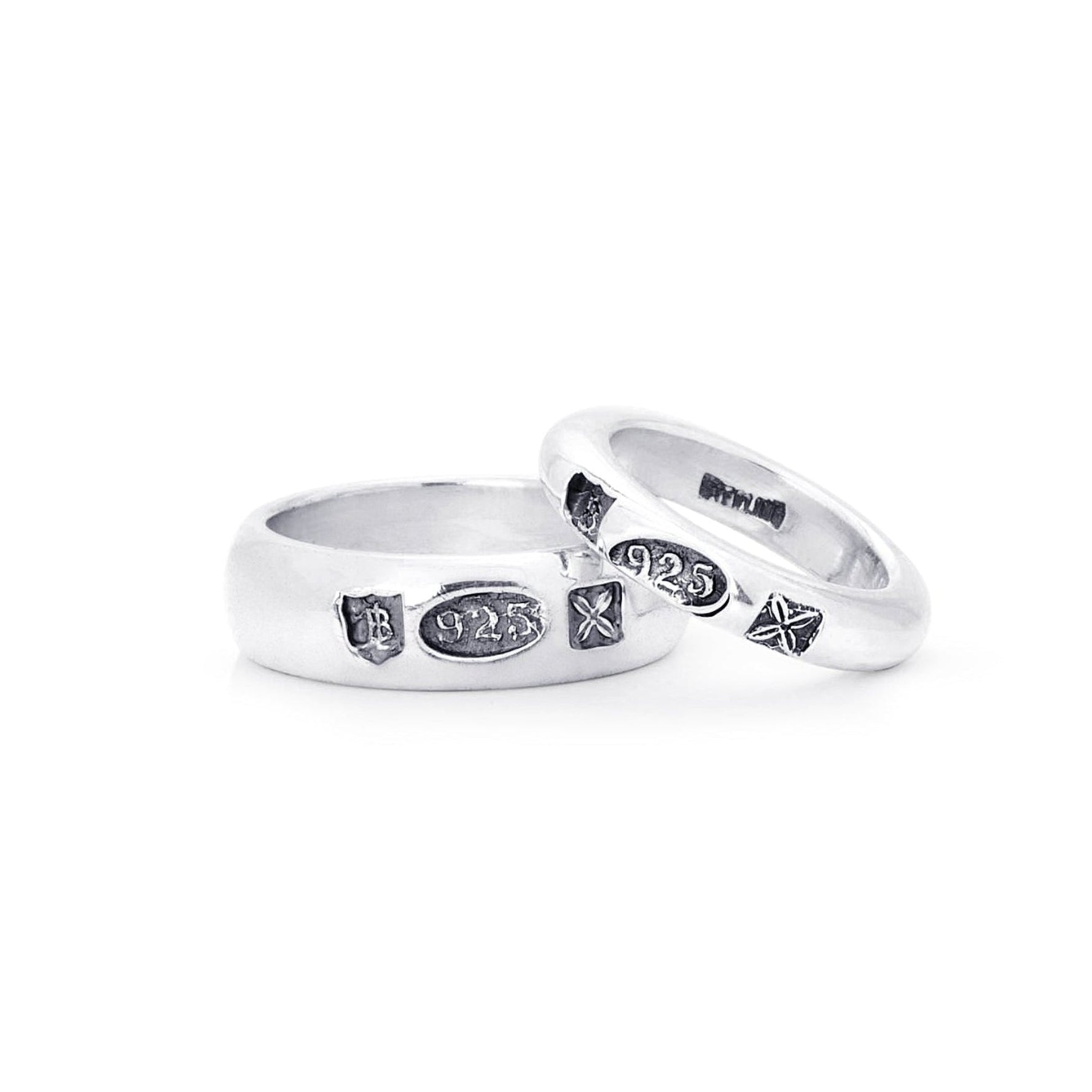 Two silver wedding bands with small blackened hallmark stamps, displayed on a clean white background.