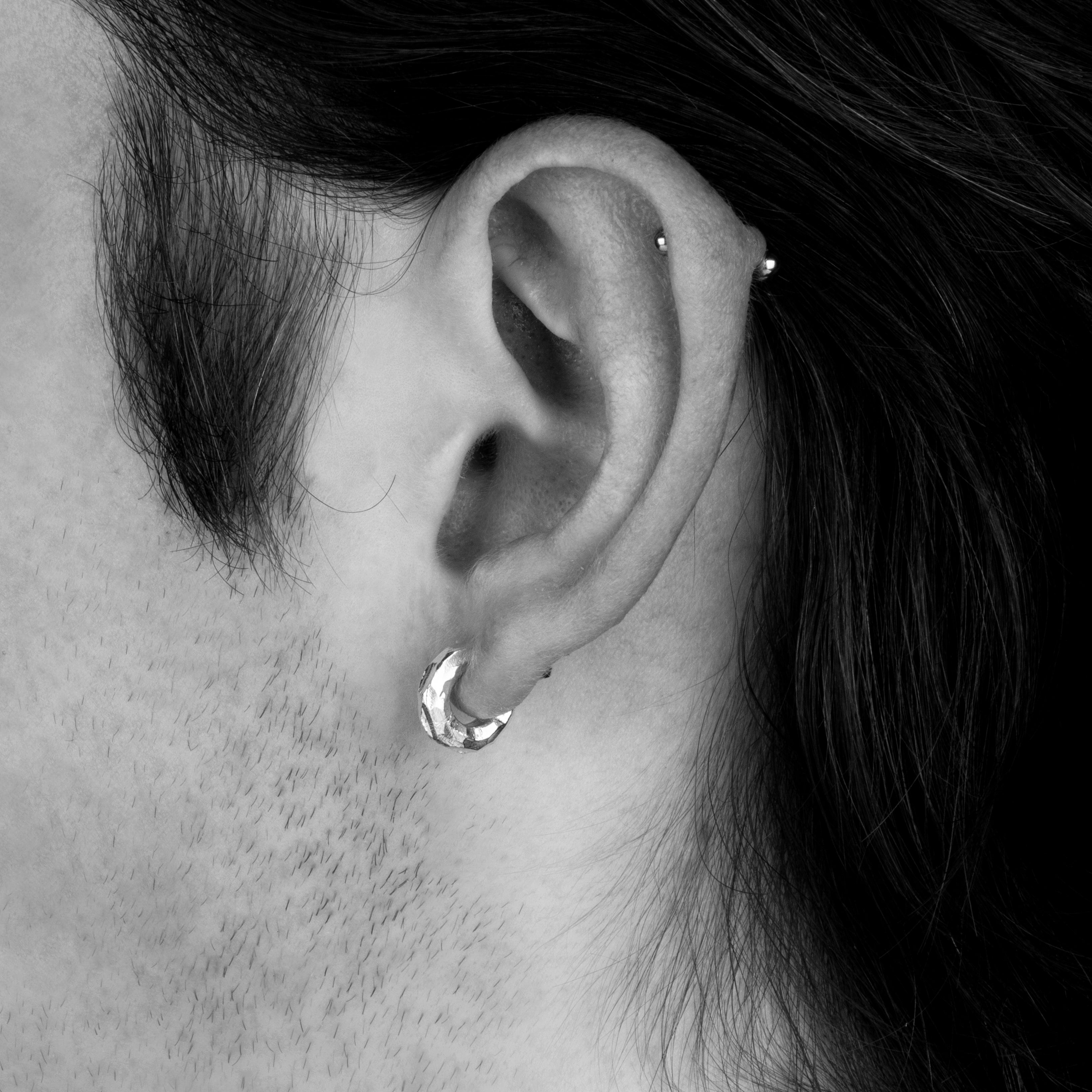 Hand crafted, Solid sterling silver hoop stud. Chiseled textured hoop on a model.