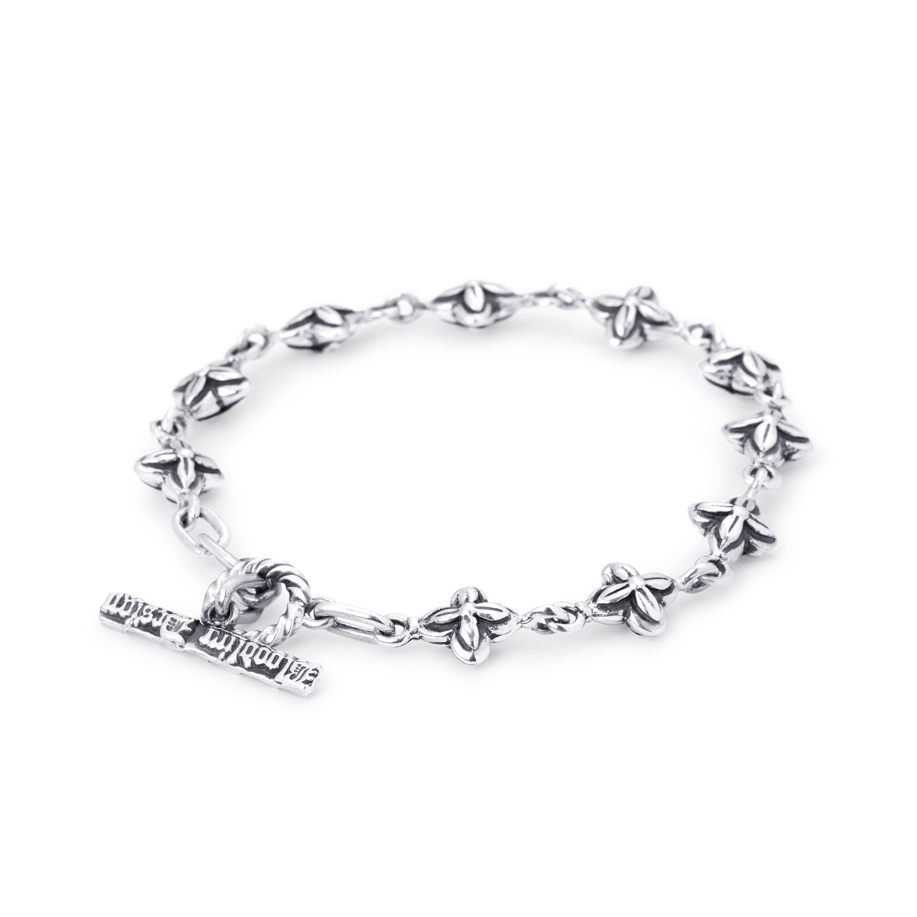 A sterling silver metal bracelet featuring a repeating floral pattern on a whote background. 