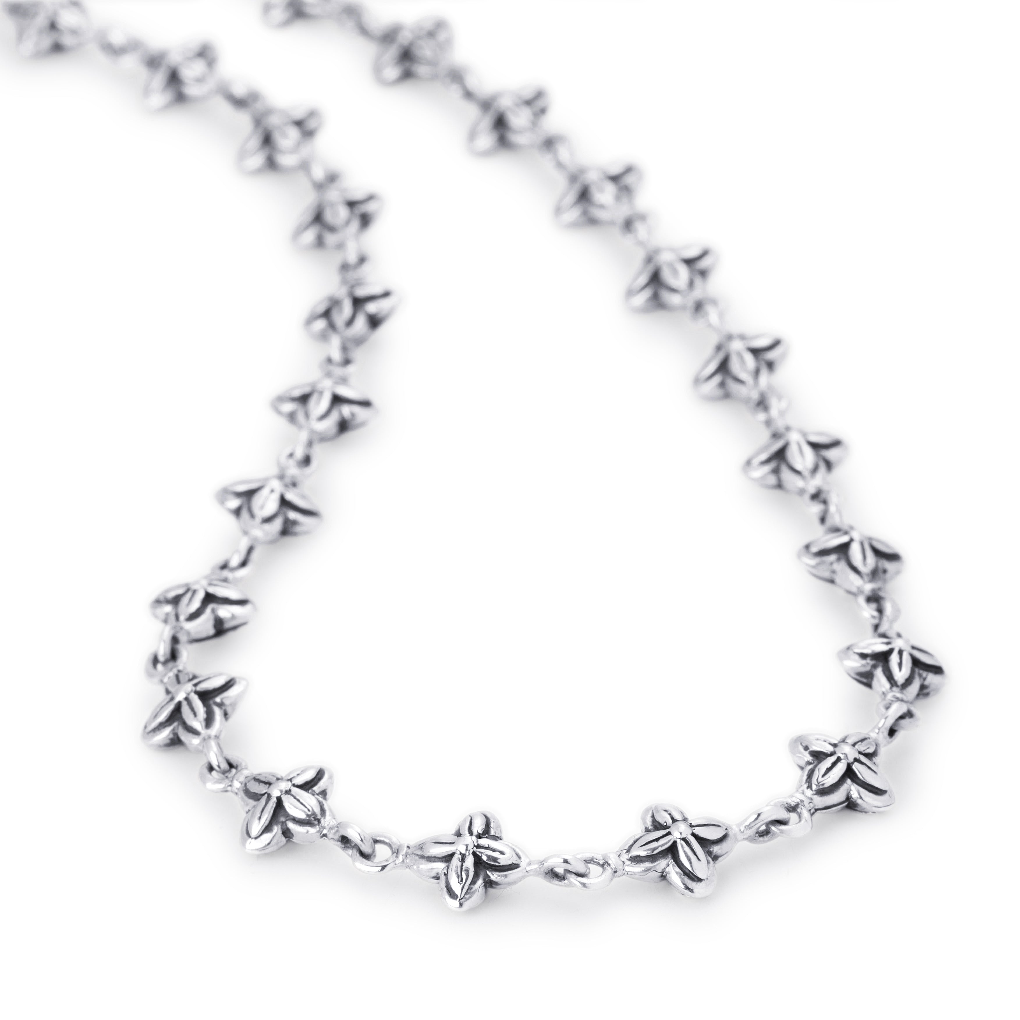 A silver link chain necklace featuring small, detailed flower-shaped charms spaced along the chain, photographed on a clean white background.