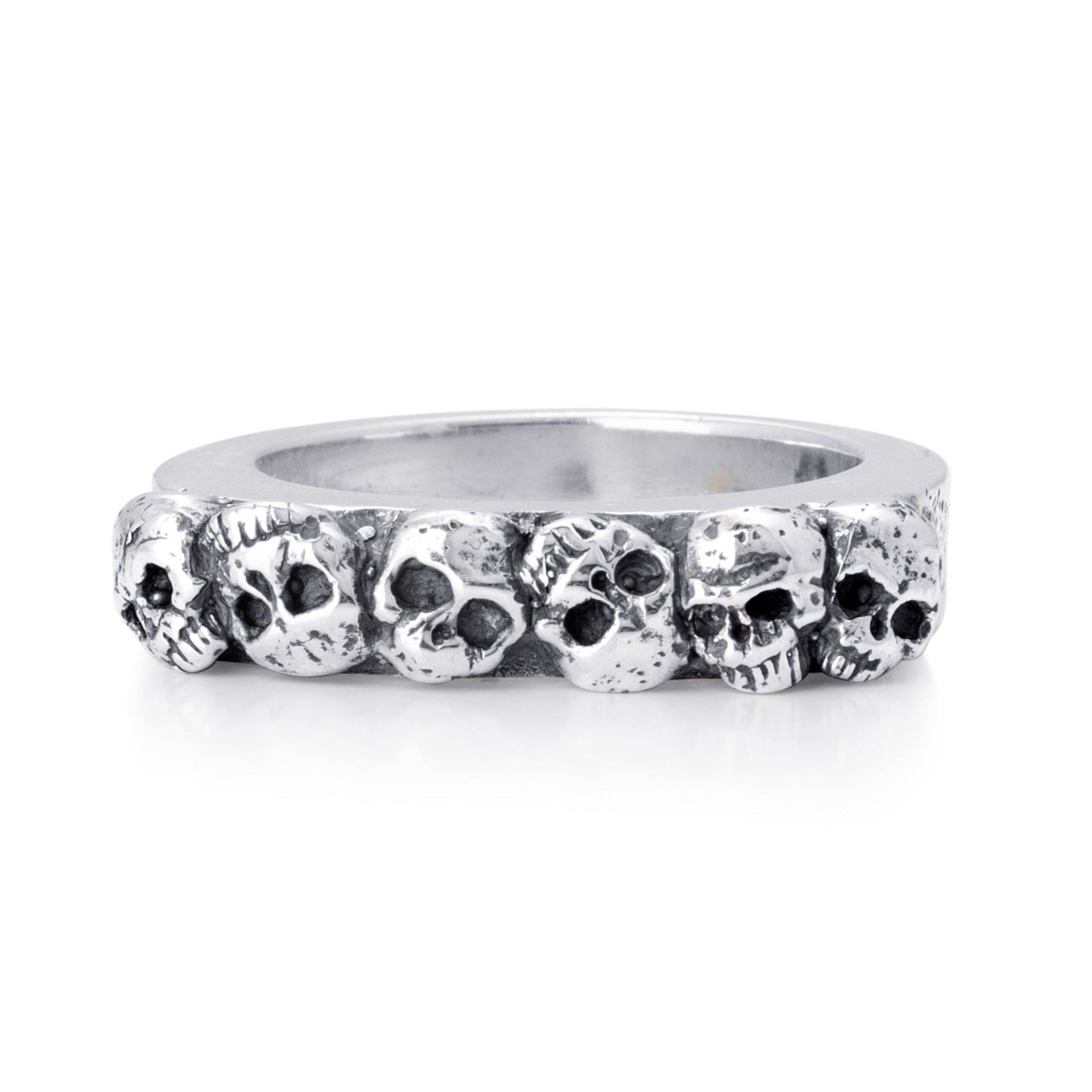 Solid sterling silver band with six skulls exposed on the top. Pitting surrounds the skulls on the top. Front view of the ring