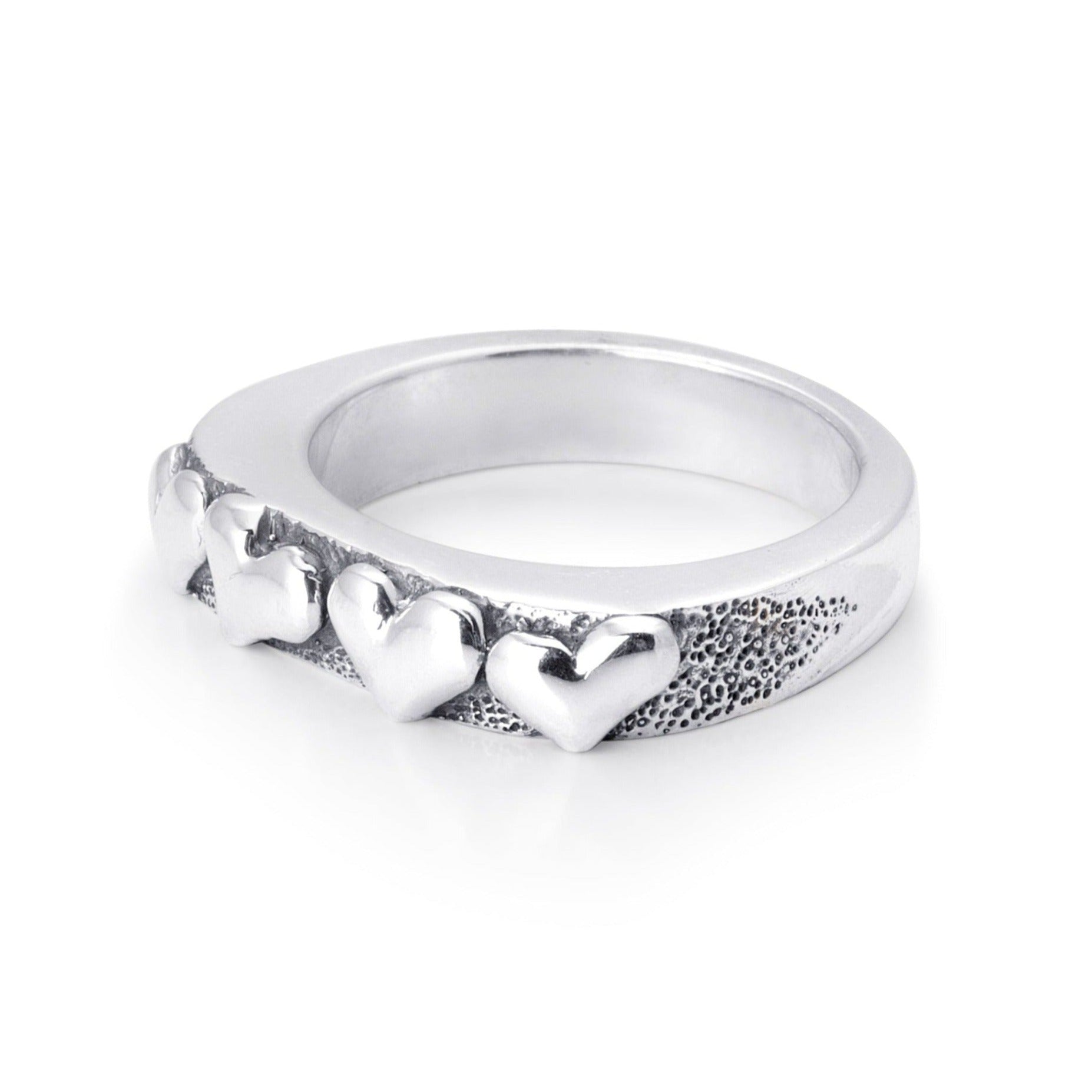 Solid sterling silver band with four hearts exposed on the top. Pitting surrounds the hearts on the top. 45 degree view of the Ring