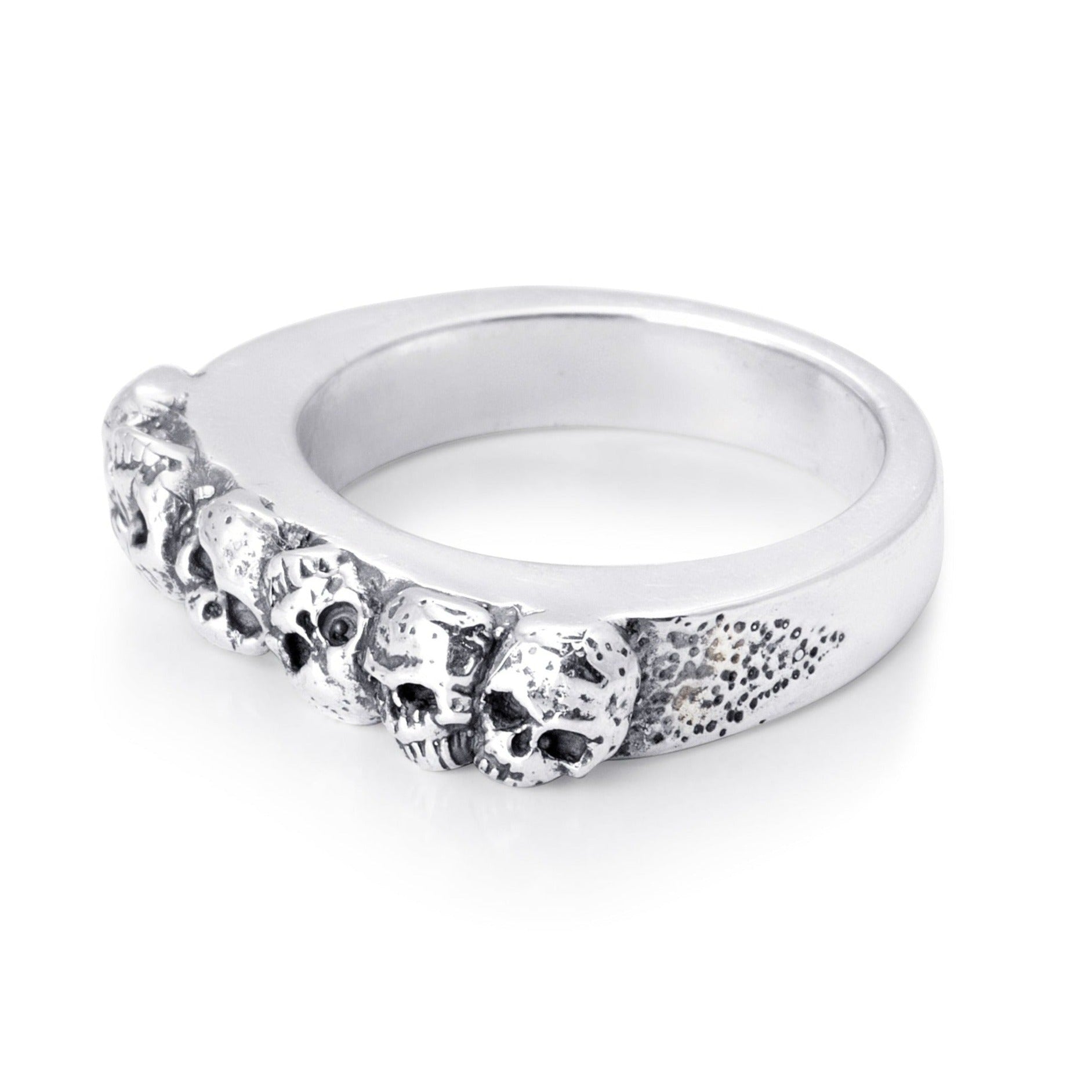 Solid sterling silver band with six skulls exposed on the top. Pitting surrounds the skulls on the top. Side view of the Ring